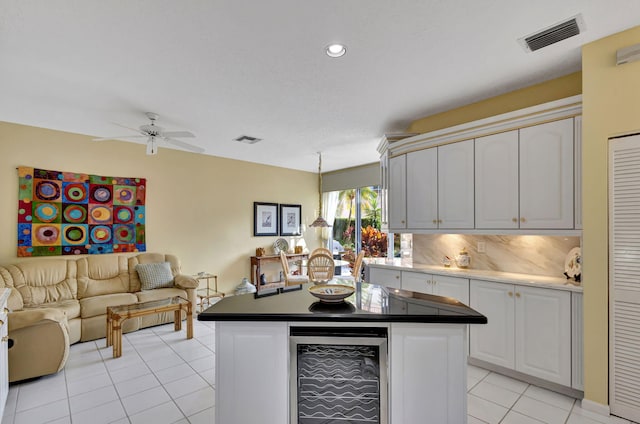 kitchen featuring a kitchen island, tasteful backsplash, white cabinetry, wine cooler, and light tile patterned floors