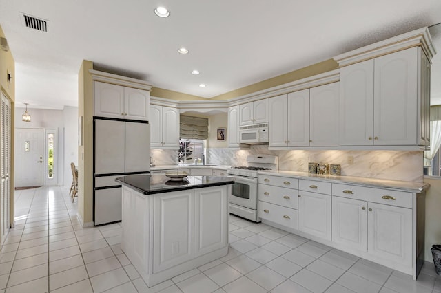 kitchen featuring a kitchen island, tasteful backsplash, sink, light tile patterned floors, and white appliances