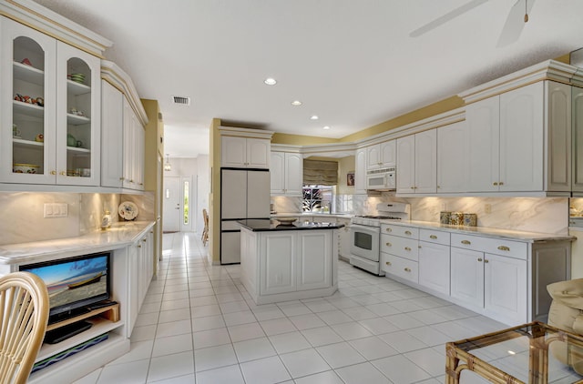 kitchen featuring light tile patterned flooring, white appliances, white cabinets, and backsplash