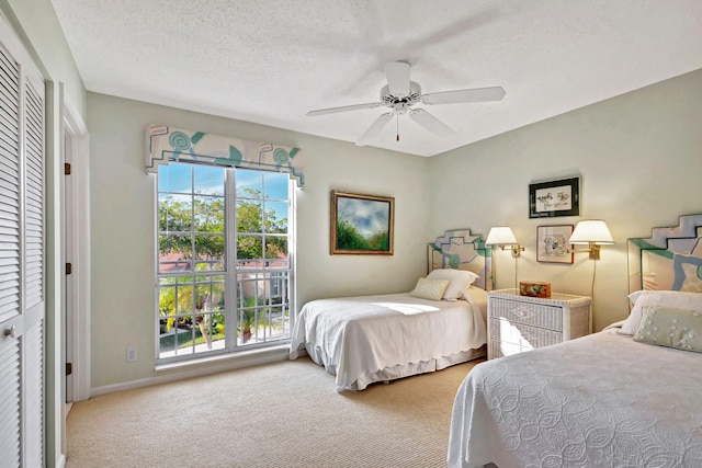 carpeted bedroom with ceiling fan, a closet, and a textured ceiling