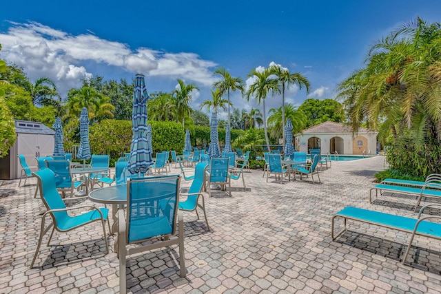 view of patio with a community pool and a storage unit