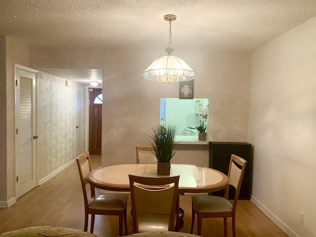 dining room with a textured ceiling, a chandelier, and hardwood / wood-style flooring