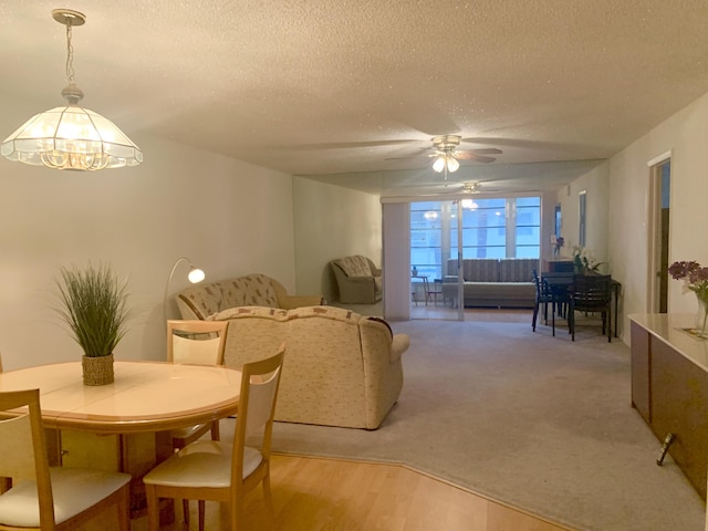 dining area featuring ceiling fan with notable chandelier, a textured ceiling, and light hardwood / wood-style flooring