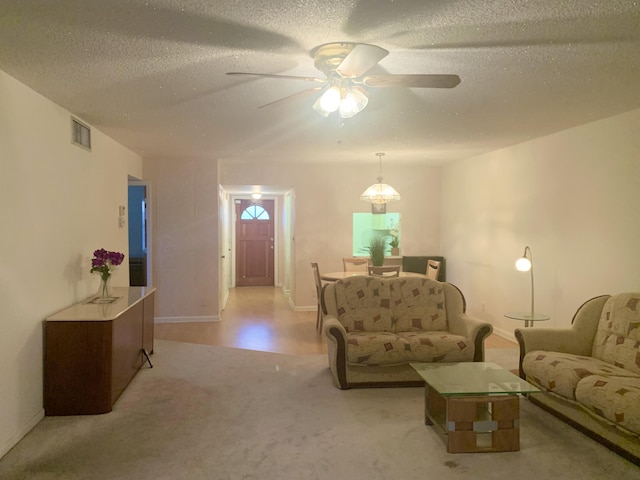 carpeted living room featuring ceiling fan and a textured ceiling