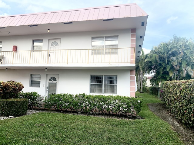 view of front of home featuring a balcony and a front yard