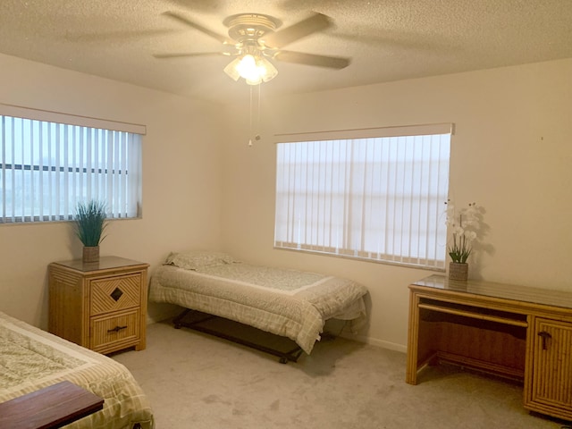 carpeted bedroom featuring ceiling fan and a textured ceiling