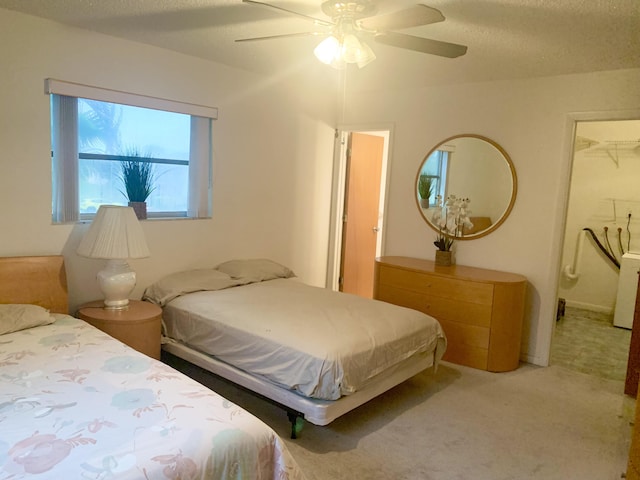 carpeted bedroom with a textured ceiling, ceiling fan, a walk in closet, and a closet