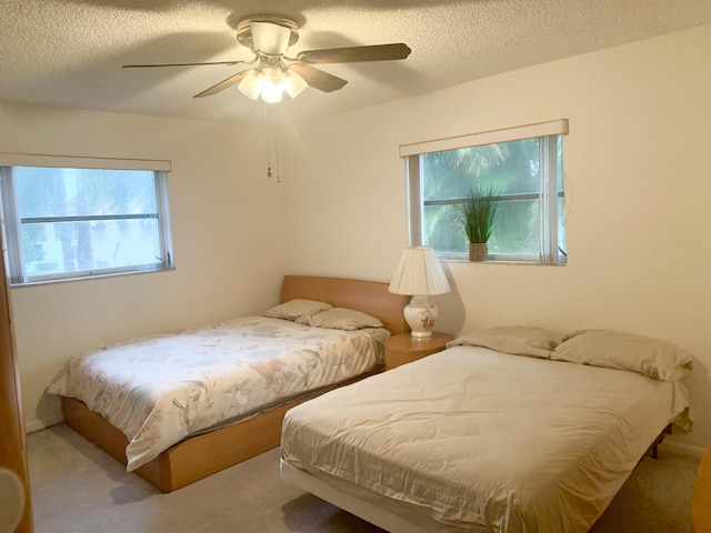 carpeted bedroom featuring ceiling fan and a textured ceiling