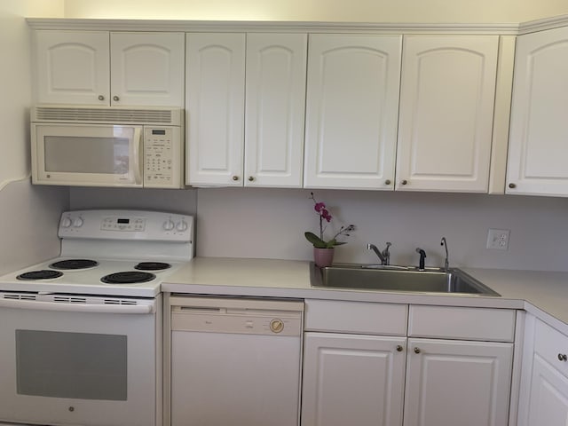 kitchen with sink, white appliances, and white cabinetry