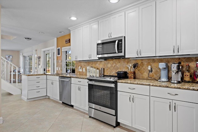 kitchen with light tile patterned floors, white cabinetry, appliances with stainless steel finishes, tasteful backsplash, and light stone counters