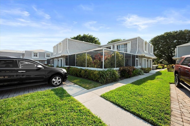 view of side of home with a lawn and glass enclosure