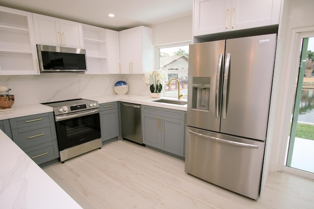 kitchen with white cabinets, stainless steel appliances, tasteful backsplash, sink, and gray cabinetry