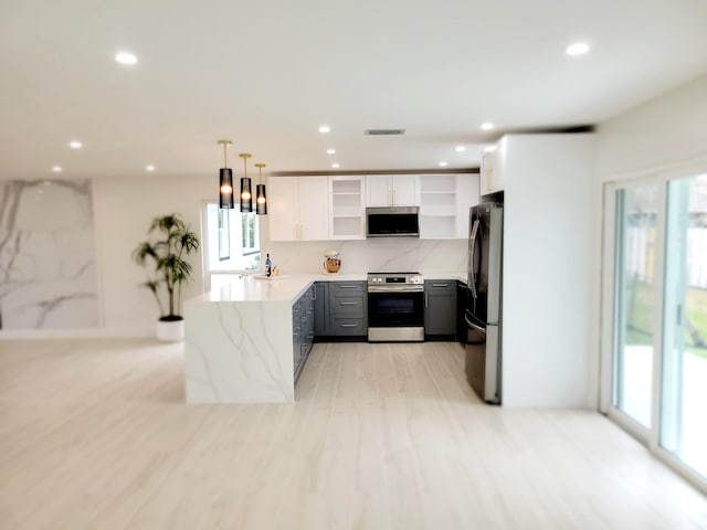 kitchen with stainless steel electric stove, light stone countertops, white cabinets, black refrigerator, and hanging light fixtures