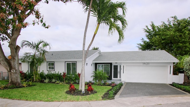 ranch-style house featuring a garage and a front lawn