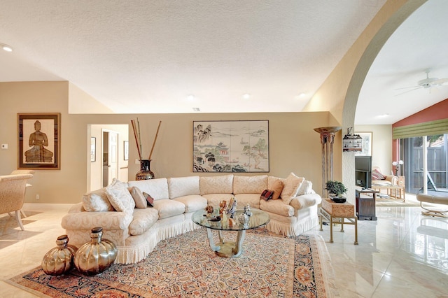 living room featuring ceiling fan, a textured ceiling, and lofted ceiling