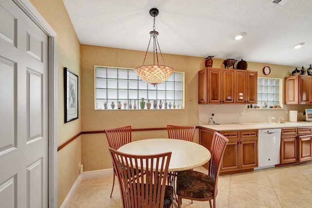 kitchen with light tile patterned floors, plenty of natural light, dishwasher, and hanging light fixtures