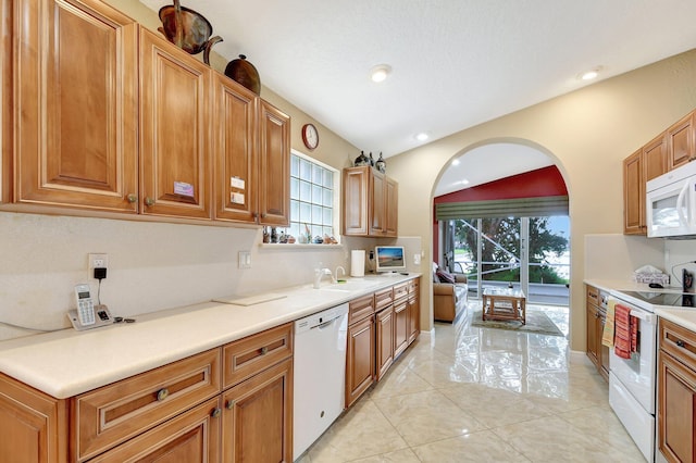 kitchen with sink, white appliances, light tile patterned floors, and lofted ceiling