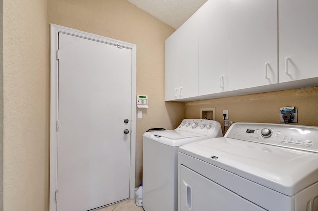 washroom with light tile patterned flooring, a textured ceiling, cabinets, and independent washer and dryer