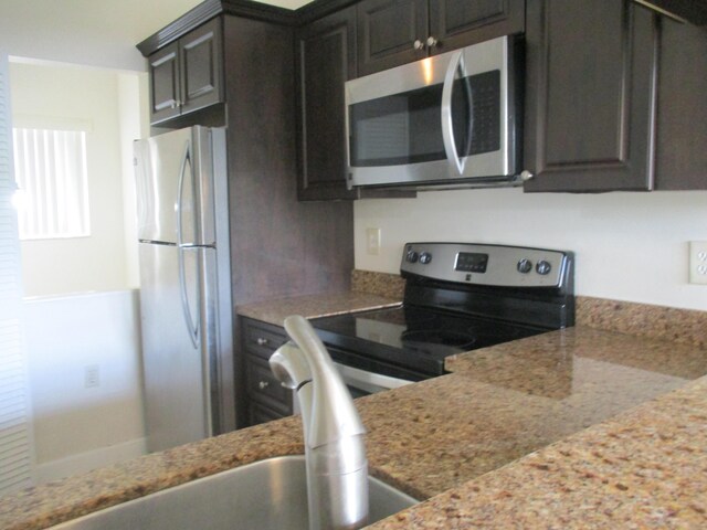 kitchen with sink, stone counters, stainless steel appliances, and light tile patterned flooring