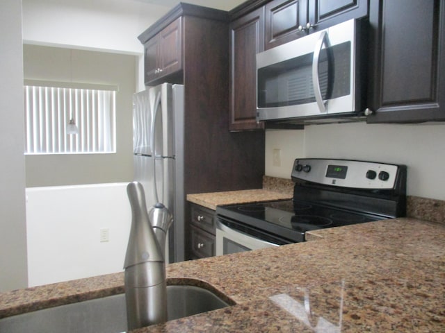 kitchen with appliances with stainless steel finishes, stone counters, and dark brown cabinetry