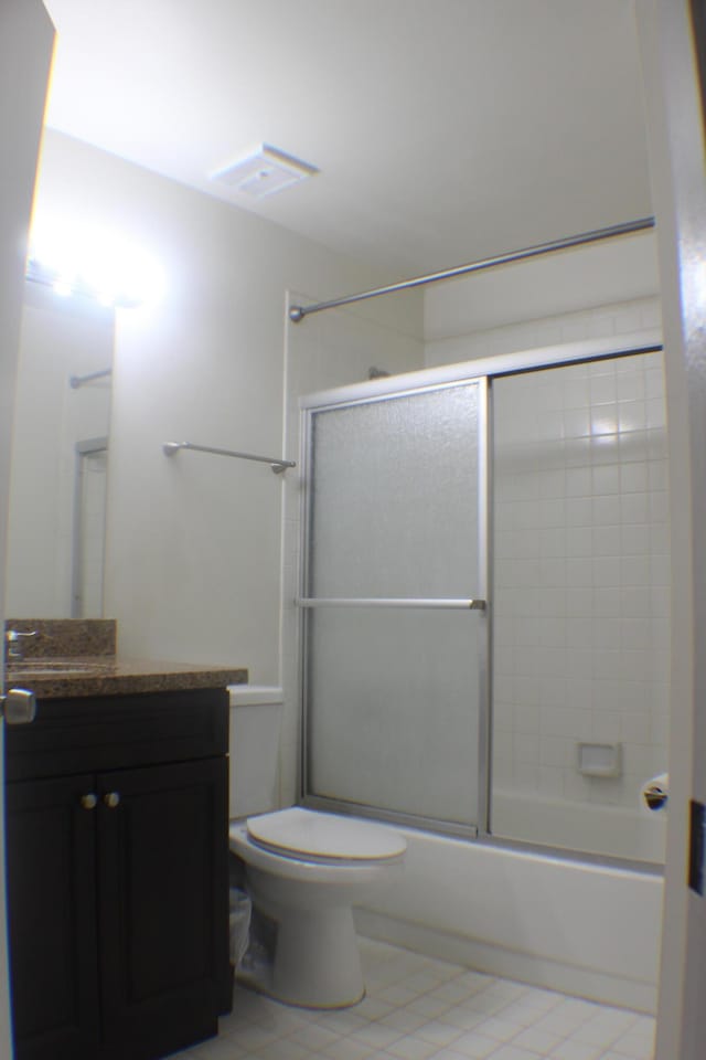 bathroom featuring enclosed tub / shower combo, vanity, toilet, and tile patterned floors