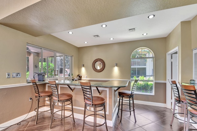 kitchen featuring a peninsula, baseboards, visible vents, and a kitchen breakfast bar