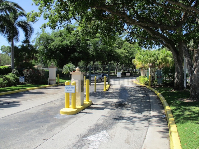 view of street with curbs, a gated entry, and a gate