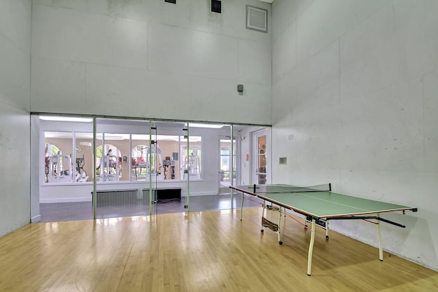 playroom featuring a high ceiling, baseboards, and wood finished floors