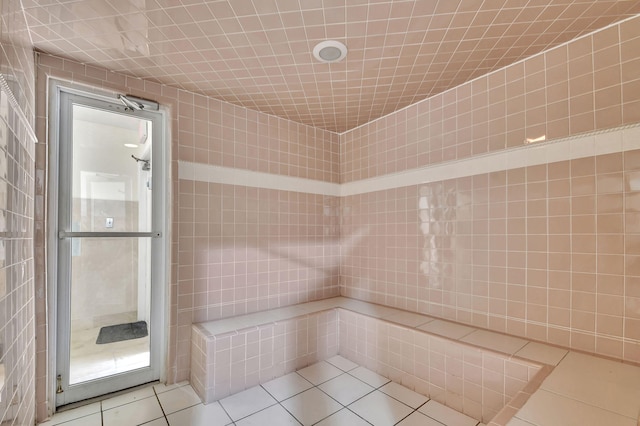 bathroom featuring tiled shower, tile patterned flooring, and tile walls