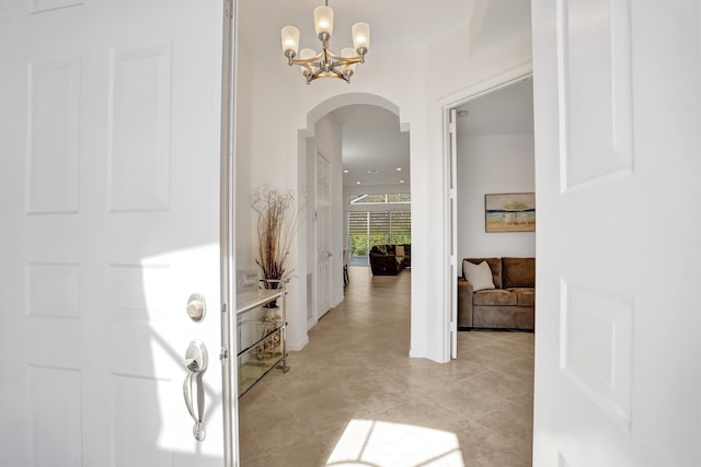 hallway featuring light tile patterned floors and an inviting chandelier