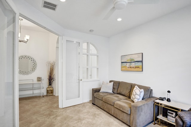 living room with light tile patterned flooring and ceiling fan with notable chandelier