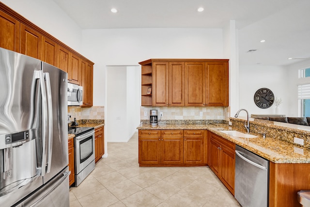 kitchen featuring tasteful backsplash, sink, light stone countertops, stainless steel appliances, and light tile patterned floors