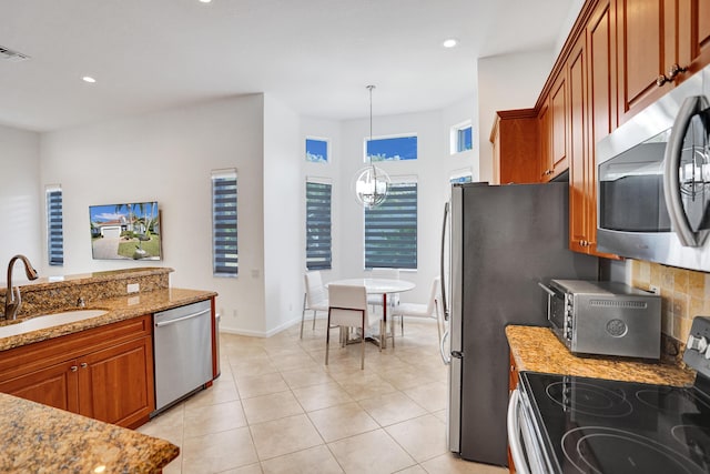 kitchen featuring decorative light fixtures, stainless steel appliances, sink, a notable chandelier, and light stone counters