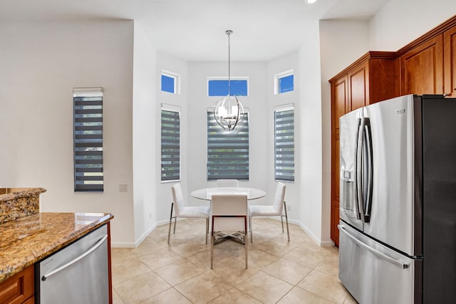 kitchen featuring appliances with stainless steel finishes, decorative light fixtures, a chandelier, light stone counters, and light tile patterned floors