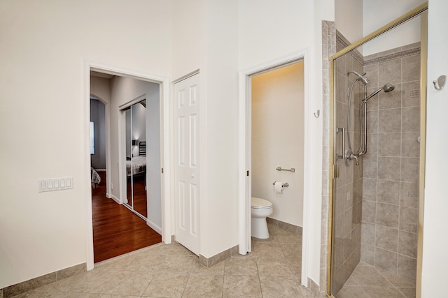 bathroom with toilet, tile patterned flooring, and walk in shower