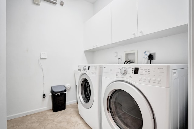 laundry area with light tile patterned floors, washing machine and dryer, and cabinets