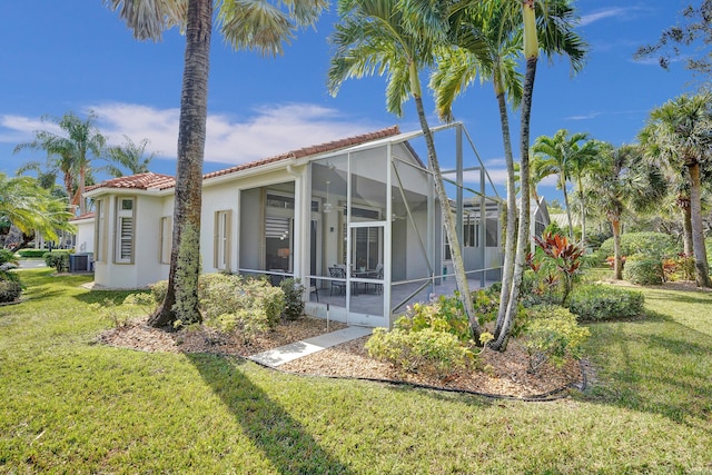 back of house featuring a lanai, a yard, and central AC unit