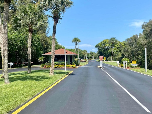 1235 S Lakes End Dr Unit 0, Fort Pierce, FL 34982 - view of asphalt road featuring traffic signs, view of scattered trees, and a gated entry