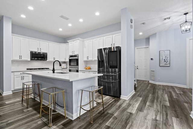 kitchen featuring sink, appliances with stainless steel finishes, pendant lighting, a kitchen island with sink, and white cabinets