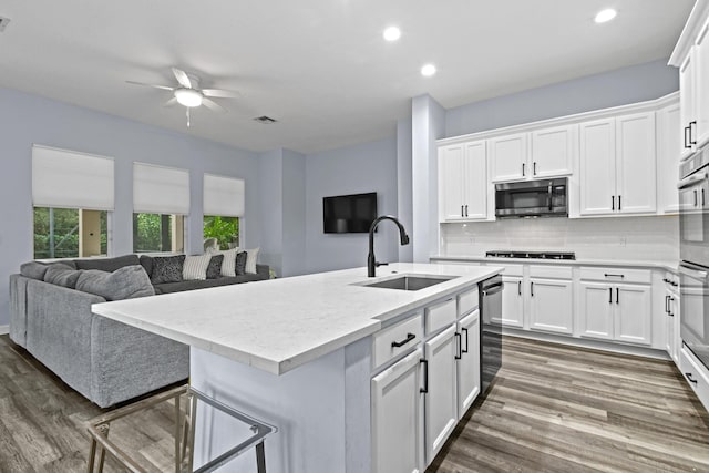 kitchen with white cabinetry, a kitchen island with sink, sink, and backsplash