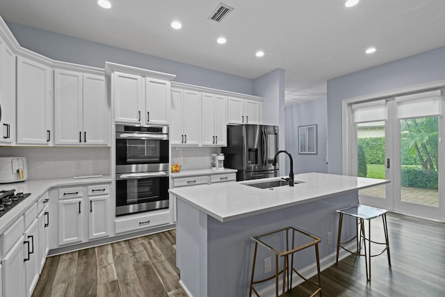 kitchen featuring sink, white cabinetry, an island with sink, stainless steel appliances, and decorative backsplash