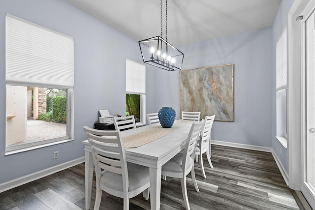 dining space featuring dark wood-type flooring and an inviting chandelier