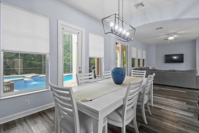 dining space with dark wood-type flooring and ceiling fan with notable chandelier