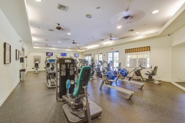 workout area featuring ceiling fan and a tray ceiling