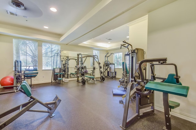 gym with a healthy amount of sunlight and a tray ceiling