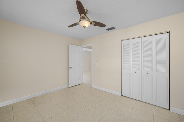 unfurnished bedroom featuring ceiling fan, a textured ceiling, a closet, and light tile patterned flooring