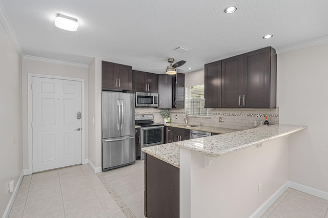 kitchen with appliances with stainless steel finishes, a kitchen bar, decorative backsplash, sink, and light tile patterned floors