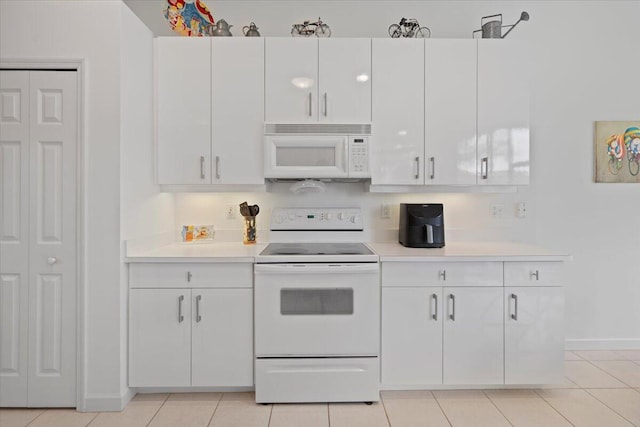 kitchen with light tile patterned flooring, white appliances, and white cabinetry