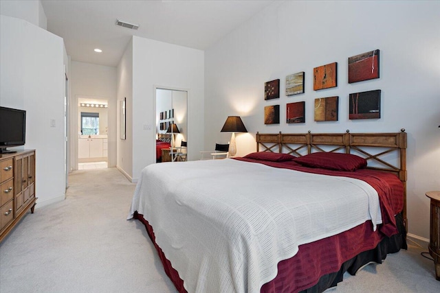 bedroom with light colored carpet and ensuite bath