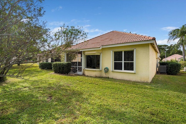 back of property featuring central air condition unit and a lawn